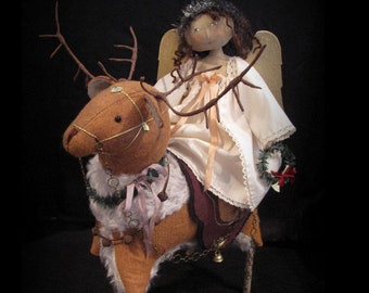 May include: A handmade doll dressed as an angel riding a reindeer. The doll is 19 inches tall and has brown hair, a white dress, and a gold halo. The reindeer is brown and has antlers. The doll and reindeer are both decorated with festive details.