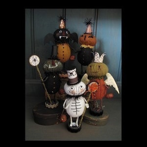 Può includere: Cinque figure di feltro fatte a mano a tema Halloween con vari costumi e accessori. Le figure sono in piedi su basi di legno e sono decorate con feltro nero, arancione, verde e bianco.