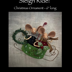 May include: A felt Christmas ornament featuring two mice riding in a green sleigh with the words "Let it Snow" on the side. The ornament is 6 inches long.