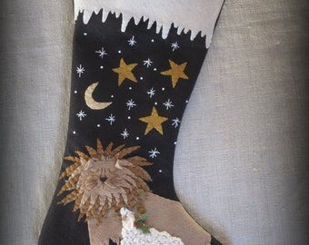May include: A black felt Christmas stocking with a white felt cuff and a snowy scene. The stocking features a lion and a lamb with a holly sprig, and a night sky with stars and a crescent moon.