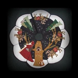 May include: A felt Christmas tree skirt with a dark blue background and white snow. The skirt features a brown tree with a squirrel, Santa Claus, and reindeer. The text "Peace" is on the tree.