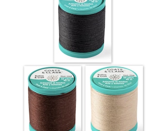 Puede incluir: Tres carretes de hilo Coats & Clark Artisanet Button & Craft en negro, marrón y beige. Cada carrete tiene una base y una parte superior turquesa con información del producto.