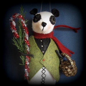 May include: A felt panda ornament wearing a red scarf and green vest, holding a candy cane and a small basket.