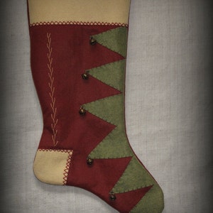 May include: A red and green Christmas stocking with a cream-colored cuff and a stitched design. The stocking is decorated with small bells.