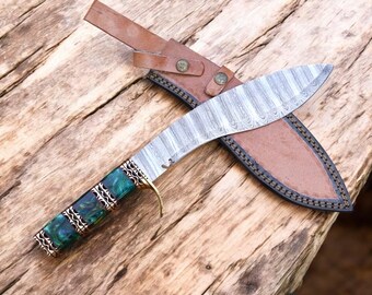May include: A green and gold handled knife with a Damascus steel blade and a brown leather sheath.