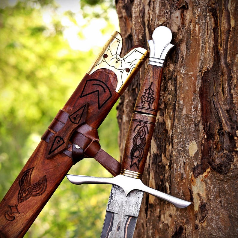 May include: A dagger with a patterned steel blade, a wooden handle featuring intricate carvings, and a polished silver pommel. The matching wooden scabbard displays dark wood grain, engraved symbols, and a decorative gold-toned metal throat.