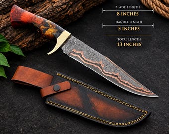 May include: A fixed-blade knife with a patterned Damascus steel blade featuring copper accents, a brass bolster, and a marbled red and black resin handle. It includes a brown leather sheath with yellow stitching. Text: BLADE LENGTH 8 INCHES, HANDLE LENGTH 5 INCHES, TOTAL LENGTH 13 INCHES.