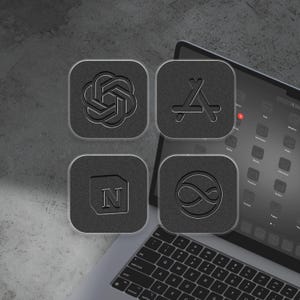 May include: Four square, dark gray app icons with embossed designs, including a stylized infinity symbol, the letter "N", a gear-like shape, and an Apple logo, are displayed on a laptop. The laptop is open on a gray surface.