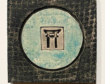 May include: Square, textured artwork with a central teal circle. Inside the circle is a silver-colored square with a black Torii gate design. The outer frame is black with a woven pattern.