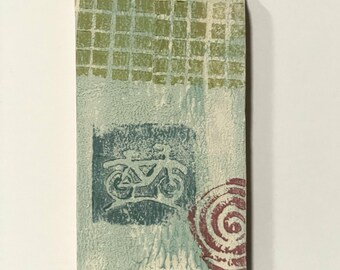 May include: Rectangular art piece with a textured surface. The top features a green grid pattern, while the center displays a bicycle image in a blue square. A red spiral design is on the right. The background is a mix of white and blue.