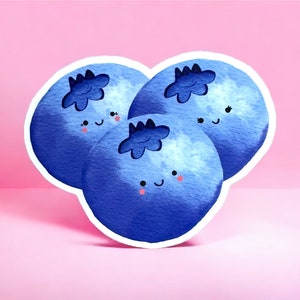 May include: Three blue blueberries with white outlines and happy faces. The blueberries are painted in a watercolour style.