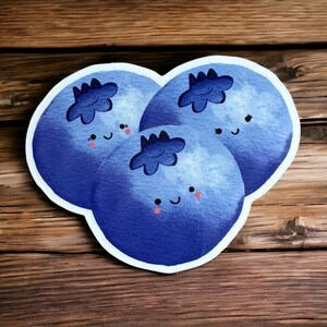 May include: Three blue blueberries with white outlines and happy faces. Each blueberry has a small, five-pointed star on top.