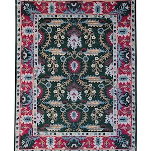 May include: A rectangular area rug with an intricate floral pattern. The rug features a dark green field with a central design of stylized flowers in shades of red, blue, and white. A red border with floral motifs frames the central design.