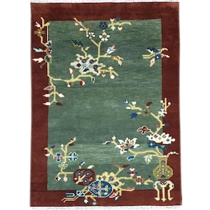 Pode incluir: Tapete retangular com um centro verde e uma borda vermelha escura. O tapete apresenta um design floral com detalhes em branco, azul e amarelo. O padrão floral é disposto ao longo das bordas do centro verde.