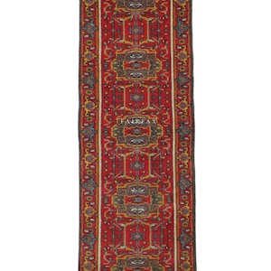 May include: A long, narrow red rug with a detailed geometric design. The rug displays repeating patterns in gold, blue, and brown. The word "FAIRFAX" is visible in three places. It has a dark border and white fringe. The rug is suitable for a hallway.