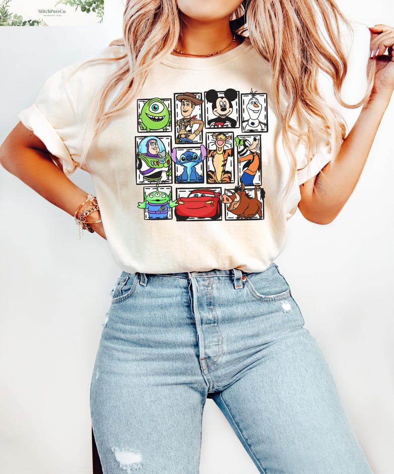 May include: Cream-colored t-shirt featuring a grid of cartoon characters including Mike Wazowski, Woody, Mickey Mouse, Olaf, Buzz Lightyear, Stitch, Tigger, and others. The shirt is paired with light blue denim jeans.