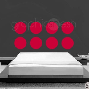 May include: A bedroom with a white bed and a gray wall with a row of six red circles.