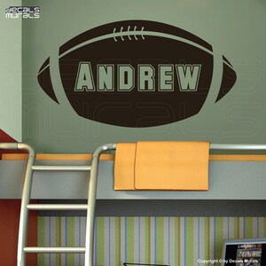 May include: A brown football-shaped wall decal with the name "ANDREW" printed in white letters.
