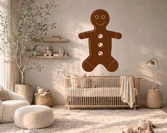 May include: A brown gingerbread man wall decal featuring a smiling face and three white circular buttons on the torso. The graphic is applied to a neutral-toned wall above a wooden crib, serving as a decorative element in a nursery setting.