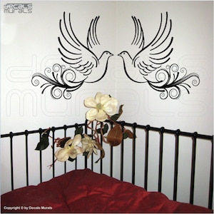 May include: Black and white wall decal featuring two stylized doves facing each other with swirling floral designs. The decal is displayed on a white wall above a black metal bed frame.