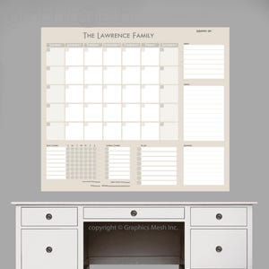 May include: A beige family calendar with the text "THE LAWRENCE FAMILY" at the top. The calendar includes a monthly layout, a section for notes, and a to-do list. The calendar is displayed above a white desk.