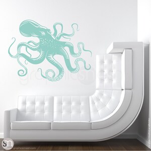 May include: A teal blue octopus wall decal with eight tentacles. The octopus is facing left and has a detailed design. The decal is shown on a white wall above a white couch.