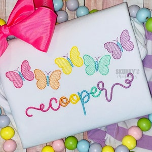 May include: A white onesie with a rainbow embroidered name "cooper" and a row of colorful butterflies.
