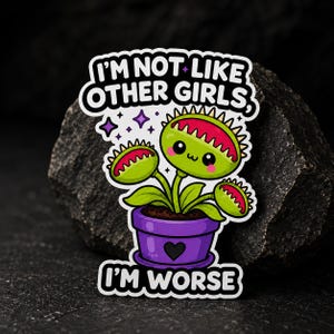 Puede incluir: Una pegatina troquelada con una Venus atrapamoscas de dibujos animados en una maceta morada con un corazón negro. La planta tiene hojas verdes, mandíbulas rojas y una cara sonriente. El texto dice I'M NOT LIKE OTHER GIRLS, I'M WORSE con estrellas.