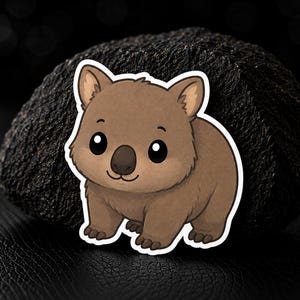 Peut inclure: Un autocollant découpé représentant une illustration de dessin animé d'un wombat brun avec de grands yeux noirs, un petit nez et des oreilles arrondies. Le wombat a un ventre brun clair et une fourrure brun foncé, souligné en blanc.