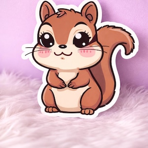 May include: A sticker featuring a cartoon squirrel with large, expressive eyes and a fluffy tail. The squirrel is primarily brown with a cream-colored belly and pink cheeks. The sticker has a white border and is set against a soft, pink background.