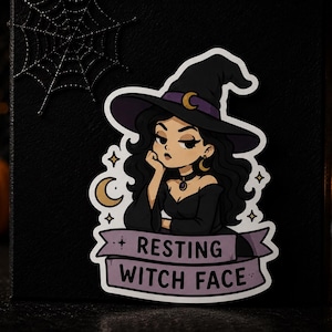 May include: A die-cut sticker featuring a cartoon illustration of a person with long black hair wearing a black witch hat with a purple band and gold crescent moon, a black choker, and a black dress, with a banner reading RESTING WITCH FACE.
