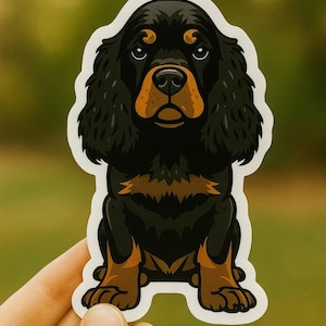Puede incluir: Adhesivo con una ilustración de dibujos animados de un perro Cavalier King Charles Spaniel. El perro está sentado, con pelaje negro y marrón, un hocico marrón y un contorno blanco. El fondo es verde borroso.