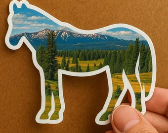 以下が含まれることがあります： 風景が描かれた馬の形をしたステッカー。馬のシルエットの中の画像は、雪をかぶった山頂、青い空、緑豊かな森がある山脈を描いています。