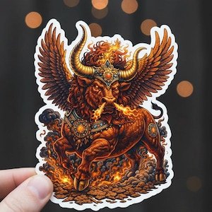 May include: A sticker depicting a winged bull, representing the Taurus zodiac sign. The illustration uses brown and gold tones, with flames issuing from the bull's nostrils and hooves. The sticker has a white border.