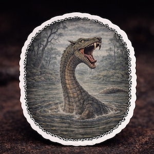 May include: Oval sticker featuring a detailed illustration of a sea serpent emerging from water. The creature has a long neck, open mouth, and sharp teeth. The background shows a misty lake and trees, framed by a decorative border.