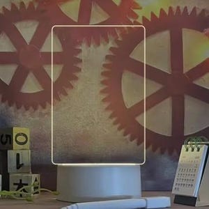 May include: A white, round, LED light base with a clear acrylic frame on top. The base has a silver finish and a white light shines from the bottom of the base.