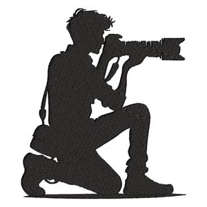 Op de afbeelding: Zwart silhouet van een fotograaf die knielt en een camera met een lange lens vasthoudt. De fotograaf heeft een cameratas over zijn schouder. De afbeelding is een gedetailleerd borduurontwerp.