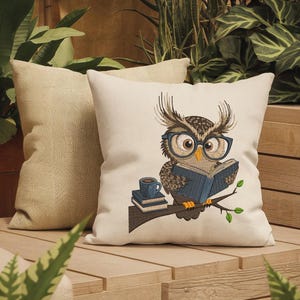 May include: A decorative pillow with an embroidered owl wearing glasses and reading a book. The owl is perched on a branch with a small stack of books and a coffee cup. A second pillow is behind it.