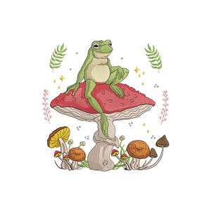 Puede incluir: Diseño bordado con una rana verde sentada sobre una seta roja con puntos blancos. La rana está rodeada de otras setas, plantas y estrellas brillantes. El diseño está sobre un fondo blanco.