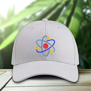 K&ouml;nnte beinhalten: Eine wei&szlig;e Baseballkappe mit einem gestickten Atom-Design. Die Atomgrafik hat einen roten Mittelpunkt, blaue Umlaufbahnen und gelbe Akzente. Die Kappe ist aus weichem Material und hat einen gebogenen Schirm.
