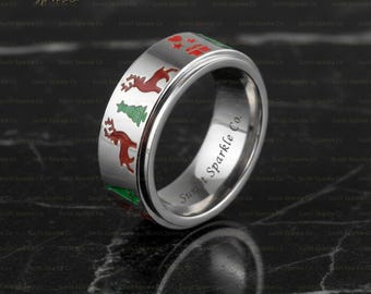 May include: A silver-colored Christmas-themed ring with red reindeer, green Christmas trees, and red gift box designs. The ring has the text "Sunlit Sparkle Co." engraved on the side.