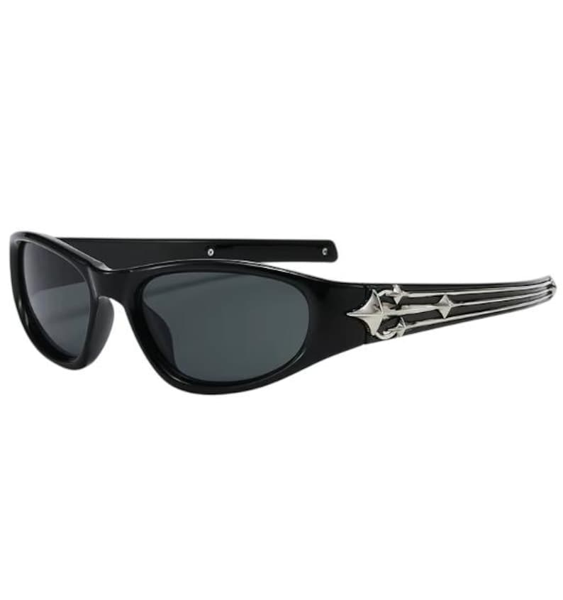 May include: Black sunglasses with a silver, ornate design on the arms. The sunglasses have a narrow, oval shape.