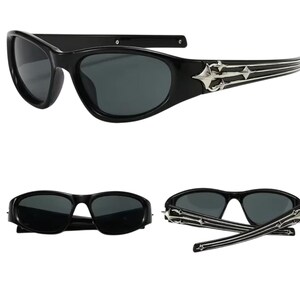 May include: Black sunglasses with a silver metal frame and a decorative design on the arms. The sunglasses have a dark lens and a curved shape.