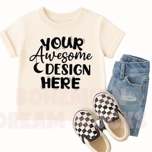 May include: A cream colored t-shirt with short sleeves and a black design that says "YOUR awesome DESIGN HERE". The shirt is paired with blue denim shorts and black and white checkered slip-on shoes.
