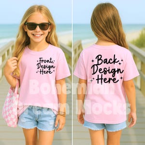 May include: A pink short-sleeved t-shirt mockup with the text "Front Design Here" on the front and "Back Design Here" on the back. The shirt is being modeled by a child wearing denim shorts.