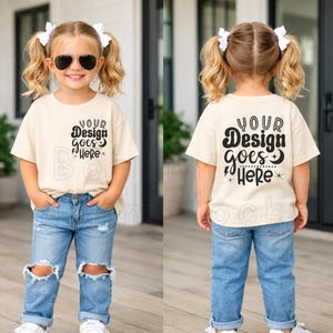 Puede incluir: Un niño viste una camiseta color crema y vaqueros azules con rodillas rasgadas. La camiseta tiene el texto "YOUR Design goes Here" impreso en la parte delantera y trasera. El niño lleva gafas de sol y lazos blancos para el pelo.