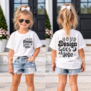 Może przedstawiać: Biała koszulka z czarnym napisem "YOUR Design goes HERE". Koszulka jest noszona z dżinsowymi szortami. Widoczny jest przód i tył koszulki. Dziewczynka ma na sobie okulary przeciwsłoneczne i białą kokardę.