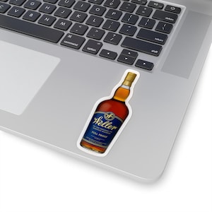 May include: A sticker featuring a bottle of Weller bourbon. The sticker has a white border and is placed on a laptop. The bottle is brown with a blue and gold label that reads "Weller" and "Full Proof".