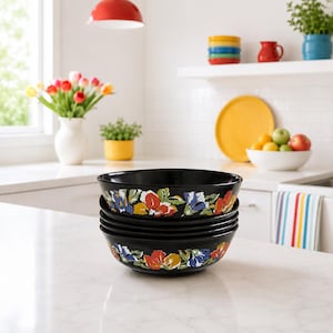Peut inclure: Une pile de quatre bols en céramique noire ornés d'un motif floral coloré sur l'extérieur. Le design présente des fleurs peintes dans des tons de rouge, jaune, bleu et vert, sur un fond noir brillant avec un bord lisse et arrondi.