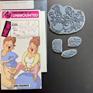 May include: An unmounted rubber stamp set with the text "Art Impressions" and "Girlfriends". The set includes a large stamp with three figures and three smaller stamps with text. The packaging features a cartoon illustration of two women.